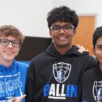 Three teenage boys posing indoors, wearing hoodies with a knight emblem; left in blue, middle in black, right in black hoodie, smiling with arms around each other.